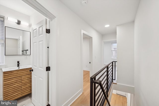 hall with light wood-type flooring and sink