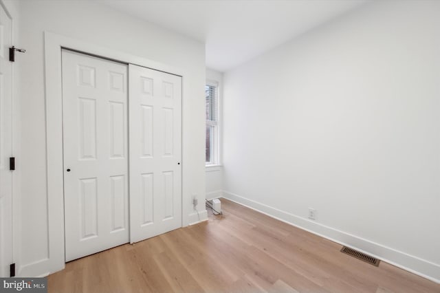 unfurnished bedroom featuring light wood-type flooring and a closet