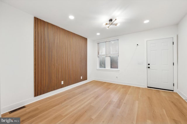 spare room featuring light wood-type flooring and an inviting chandelier