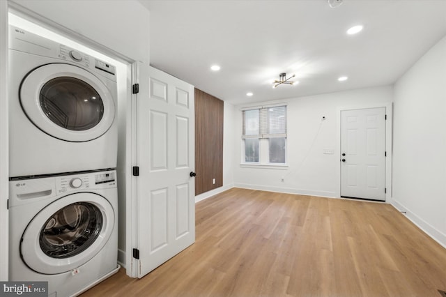 laundry area with stacked washer / drying machine and light wood-type flooring