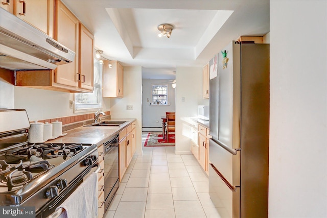 kitchen featuring light brown cabinets, sink, gas range oven, a tray ceiling, and stainless steel refrigerator