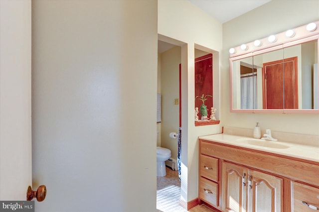 bathroom with tile patterned floors, vanity, toilet, and baseboard heating