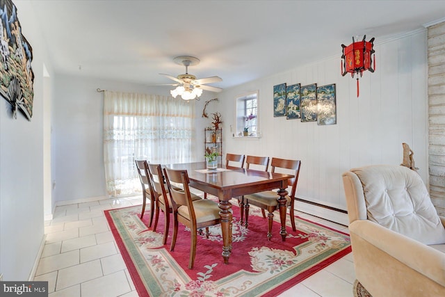 tiled dining area featuring a baseboard radiator, ceiling fan, and wooden walls