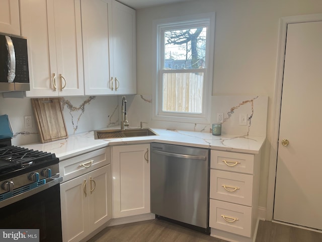 kitchen with light stone counters, sink, white cabinets, and appliances with stainless steel finishes