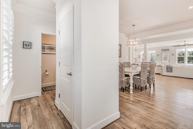 hall with crown molding, light hardwood / wood-style flooring, and a notable chandelier