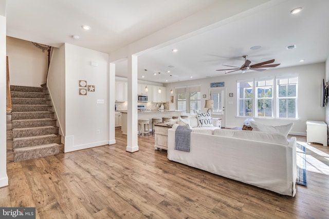 living room featuring ceiling fan, sink, and light hardwood / wood-style flooring