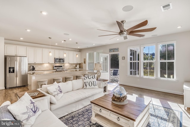 living room featuring ceiling fan, light hardwood / wood-style flooring, and sink