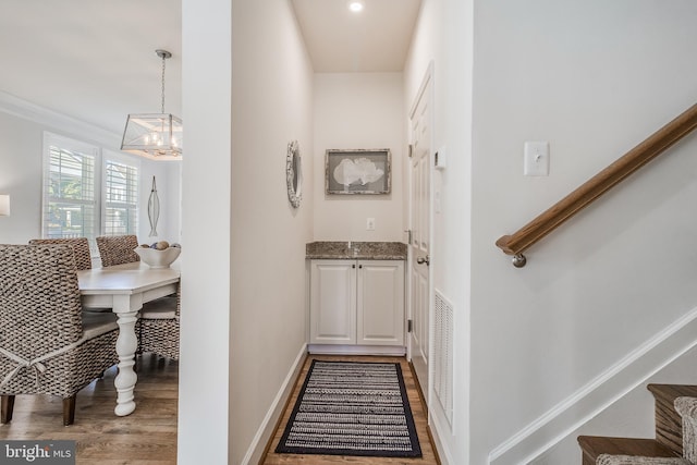 hall featuring an inviting chandelier, ornamental molding, and light hardwood / wood-style flooring