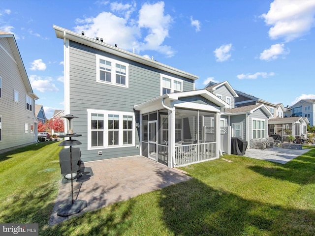 back of house featuring a yard, a patio area, and a sunroom