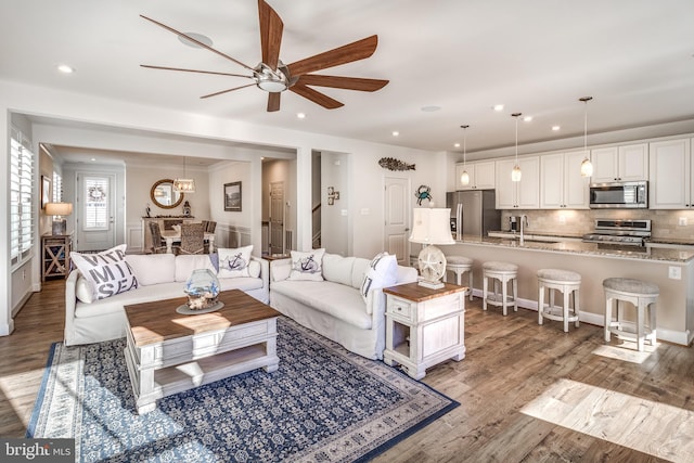 living room with ceiling fan, light hardwood / wood-style floors, and sink