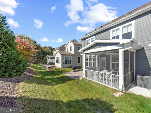 rear view of house featuring a yard, a patio, central AC unit, and a sunroom