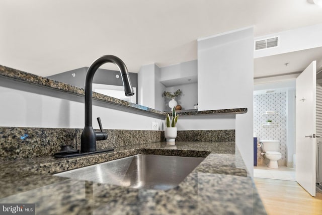 interior details with light hardwood / wood-style flooring, dark stone countertops, and sink