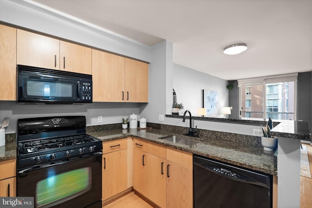 kitchen featuring light brown cabinets, black appliances, sink, dark stone countertops, and kitchen peninsula