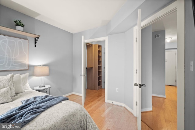 bedroom with a walk in closet, a closet, and wood-type flooring