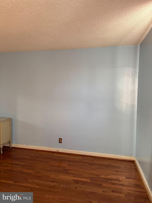 empty room with dark hardwood / wood-style flooring and a textured ceiling