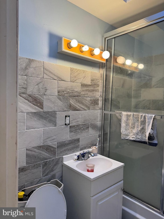 bathroom with a shower with door, vanity, and tile walls