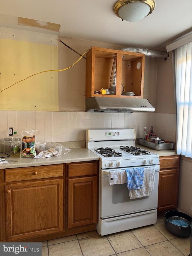 kitchen featuring backsplash, ventilation hood, and white gas range oven