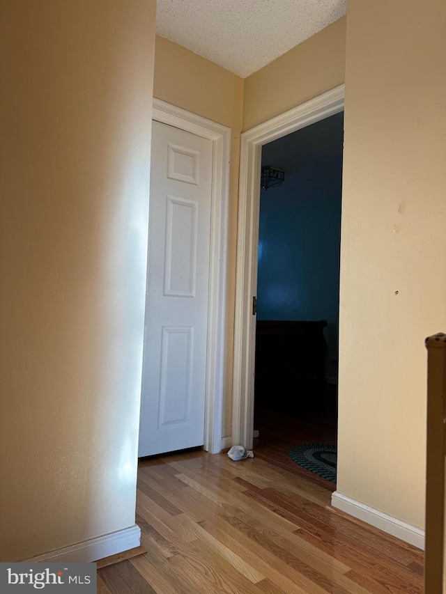 hallway featuring light hardwood / wood-style floors and a textured ceiling