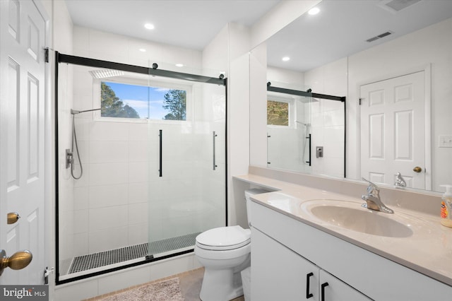 bathroom featuring tile patterned flooring, a shower with door, vanity, and toilet