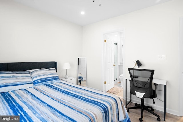 bedroom featuring connected bathroom and light hardwood / wood-style floors