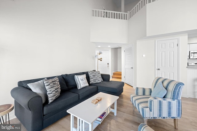 living room featuring light wood-type flooring and a towering ceiling