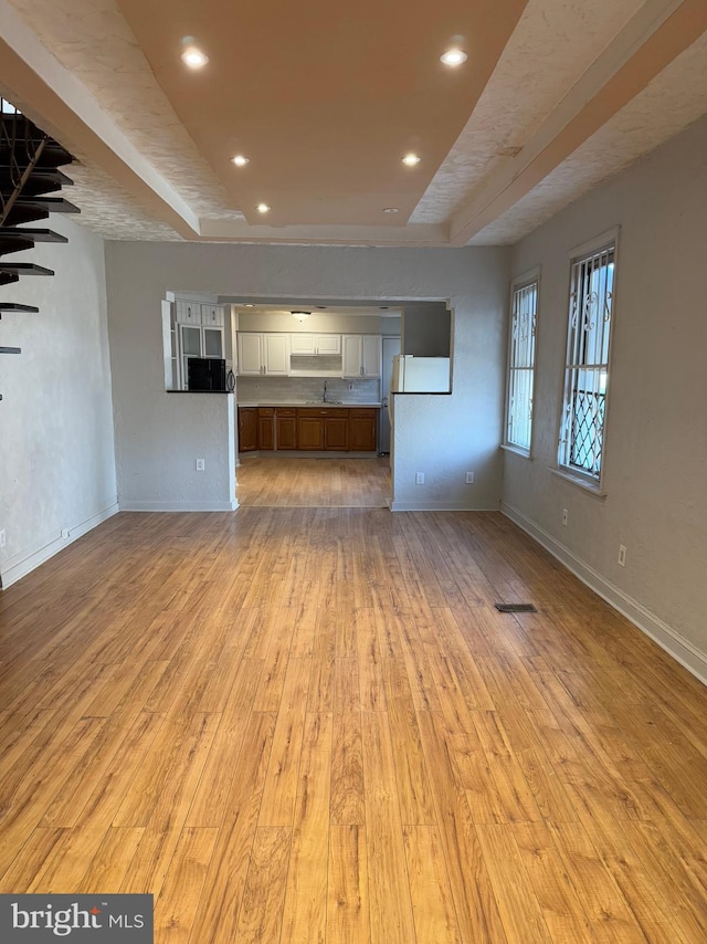 unfurnished living room with light wood-type flooring and sink