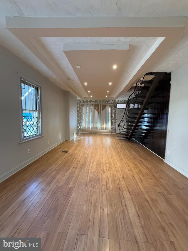 unfurnished living room with light wood-type flooring and a raised ceiling