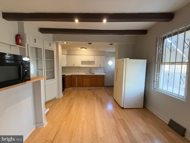 kitchen with white fridge, white cabinetry, tasteful backsplash, and light hardwood / wood-style flooring