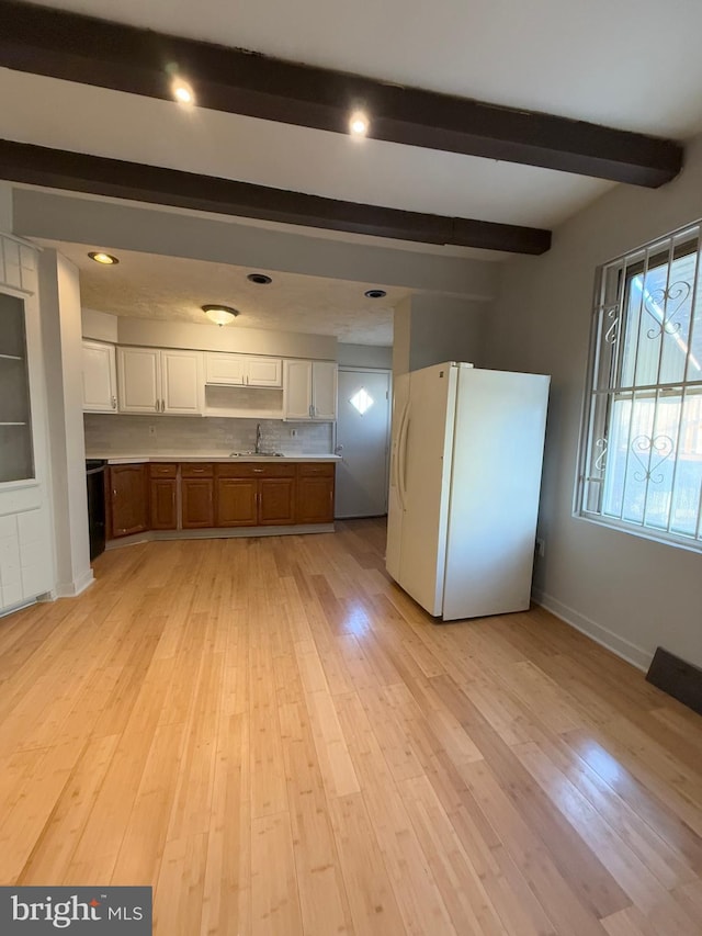 kitchen featuring white cabinets, white fridge, light hardwood / wood-style floors, and beamed ceiling