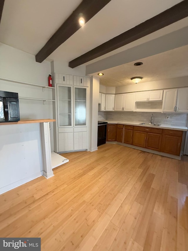 kitchen featuring sink, tasteful backsplash, beamed ceiling, white cabinets, and light wood-type flooring