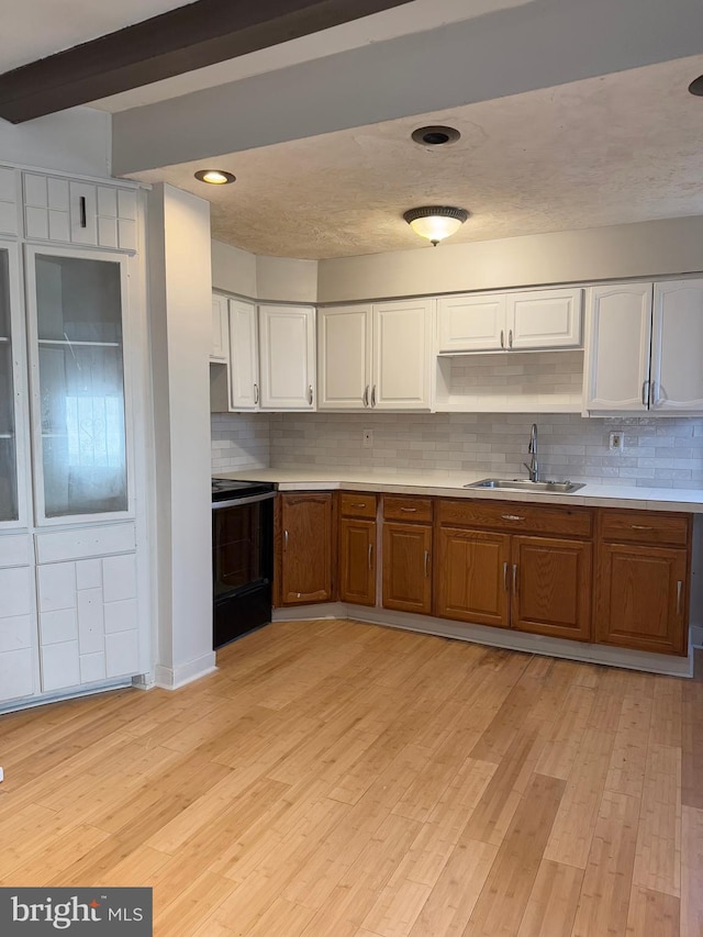 kitchen with backsplash, sink, beamed ceiling, range, and white cabinetry