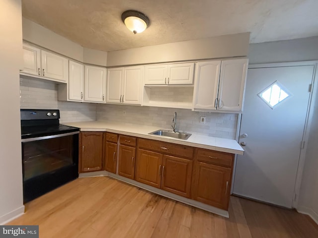 kitchen featuring backsplash, electric range, sink, and white cabinets