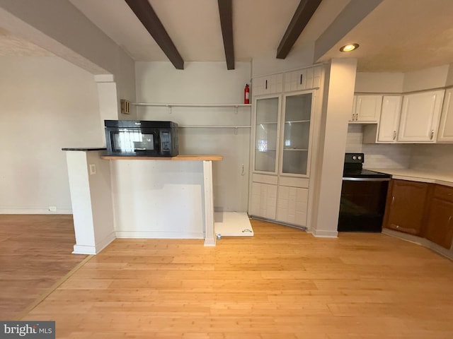 kitchen featuring beam ceiling, light hardwood / wood-style floors, white cabinetry, and black appliances