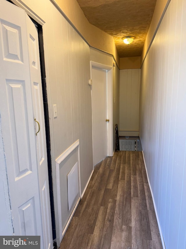 hallway featuring dark hardwood / wood-style flooring, wooden ceiling, and wood walls