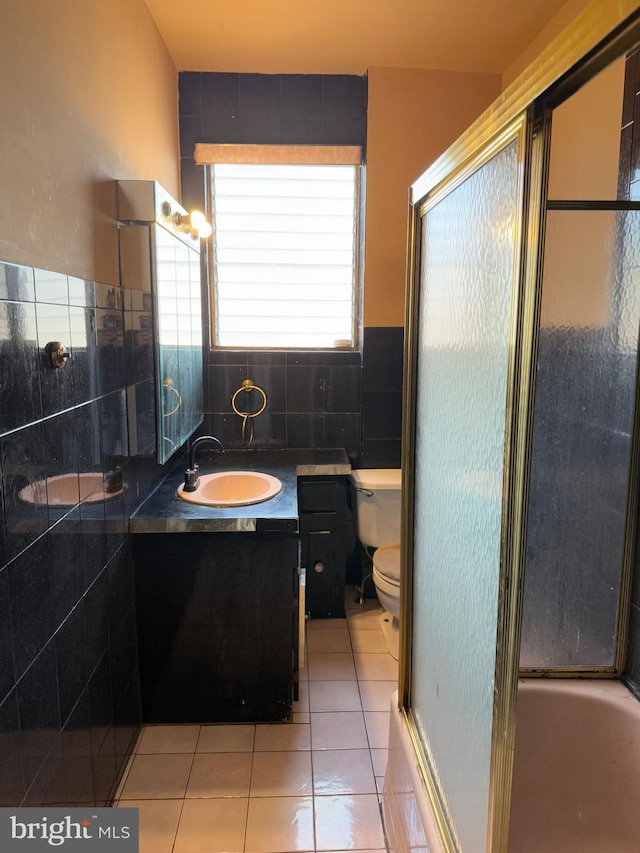 full bathroom with vanity, combined bath / shower with glass door, tile patterned flooring, toilet, and tile walls