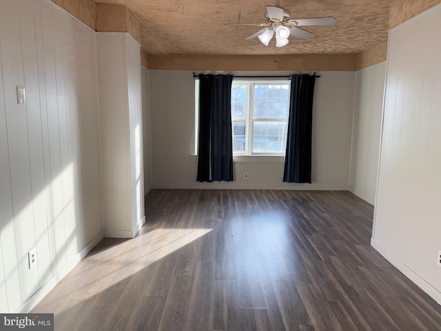 empty room featuring dark hardwood / wood-style flooring, ceiling fan, and wooden walls