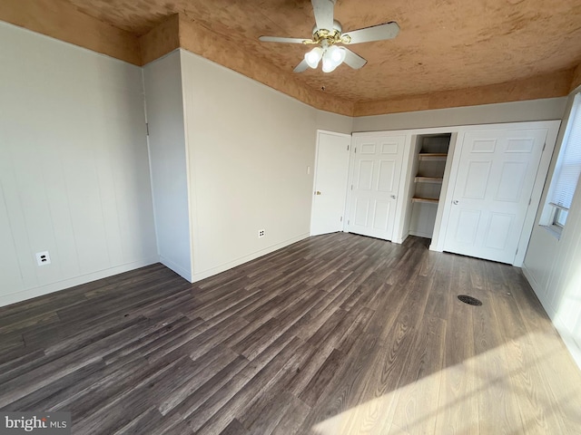 unfurnished bedroom featuring ceiling fan, dark hardwood / wood-style flooring, and a closet