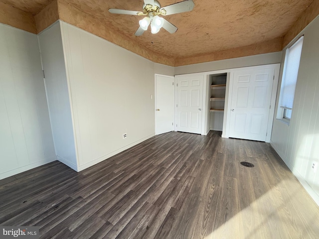 unfurnished bedroom with ceiling fan, dark hardwood / wood-style floors, and a closet