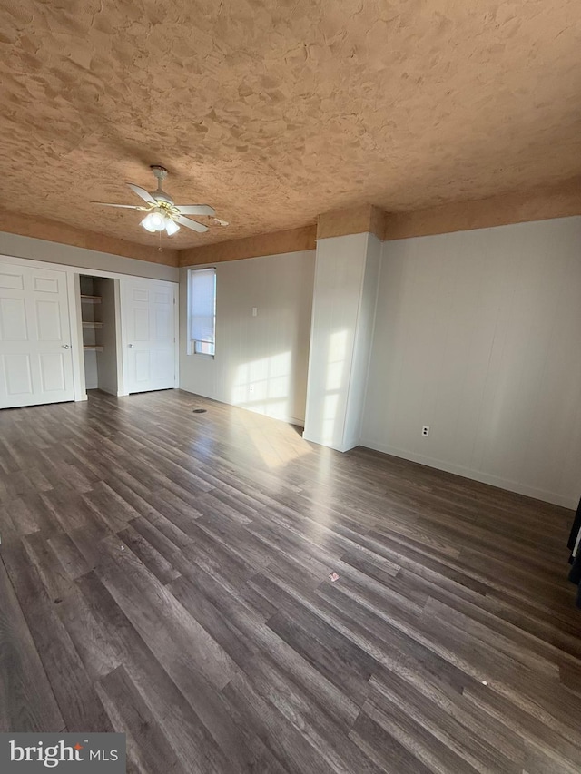 unfurnished living room featuring ceiling fan and dark wood-type flooring