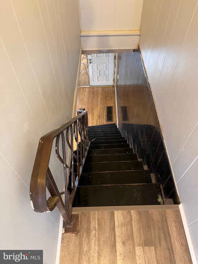 stairway with hardwood / wood-style flooring and wood walls