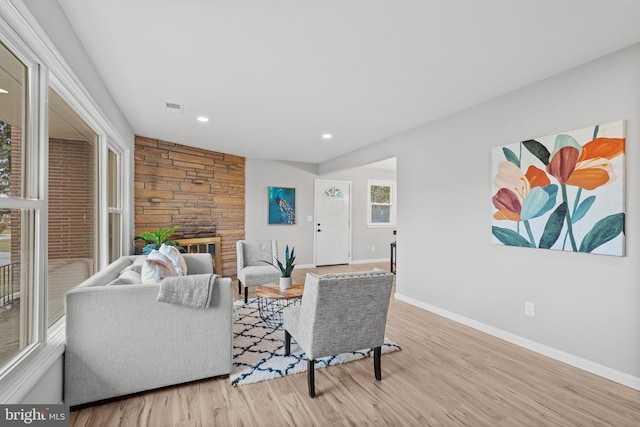 living room with light hardwood / wood-style flooring and a stone fireplace