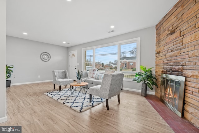 living room featuring a stone fireplace and light wood-type flooring