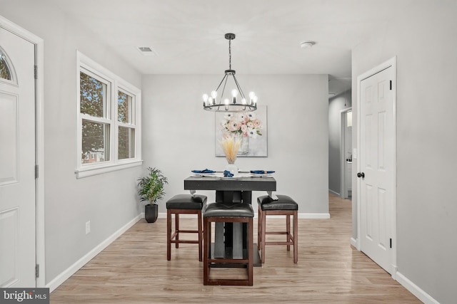 dining area with light hardwood / wood-style flooring and an inviting chandelier