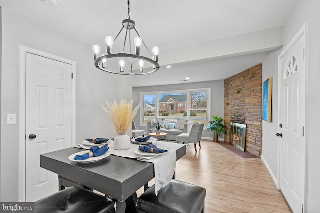 dining space featuring a fireplace, a chandelier, and light hardwood / wood-style floors