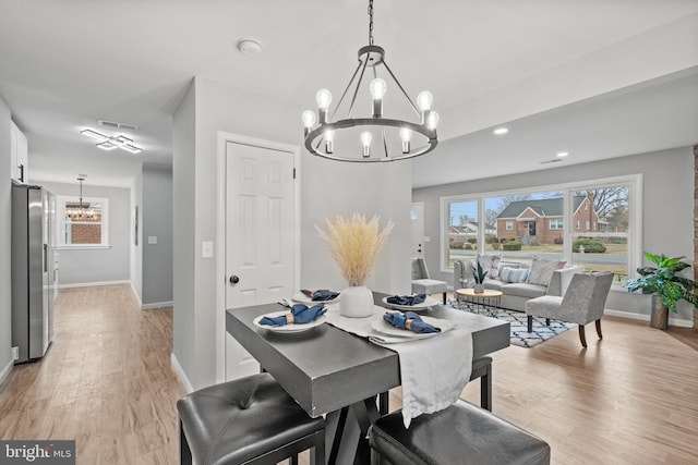 dining area with light hardwood / wood-style floors and a notable chandelier