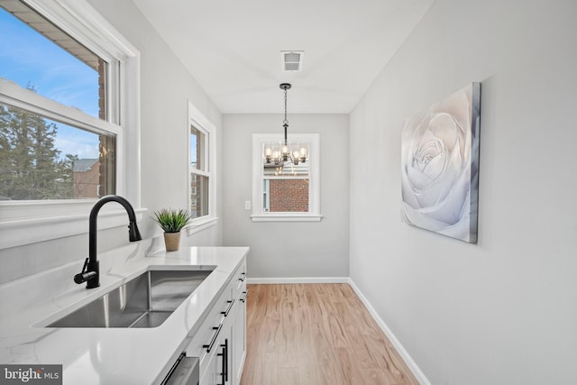 kitchen with sink, decorative light fixtures, a chandelier, light hardwood / wood-style floors, and white cabinetry