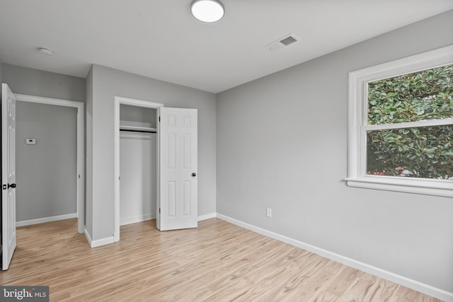 unfurnished bedroom with a closet and light wood-type flooring