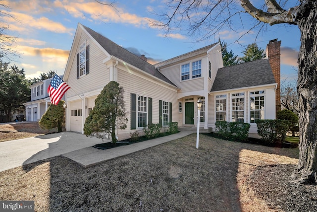 view of front of property featuring driveway, a shingled roof, and a chimney