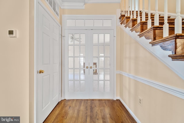 entrance foyer featuring baseboards, stairway, ornamental molding, wood finished floors, and french doors