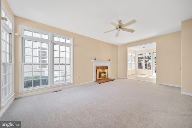 unfurnished living room featuring a brick fireplace, light carpet, plenty of natural light, and ceiling fan